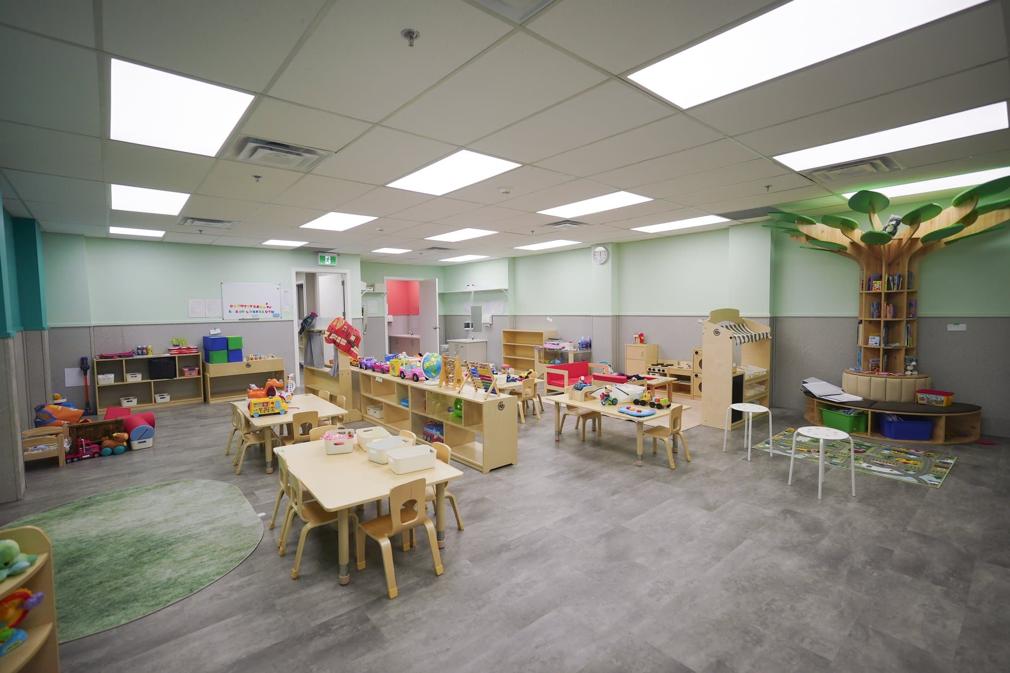 Tiny Genius Daycare bright toddler classroom with sensory tables, custom wooden tree, and safe play stations in Summerside Edmonton